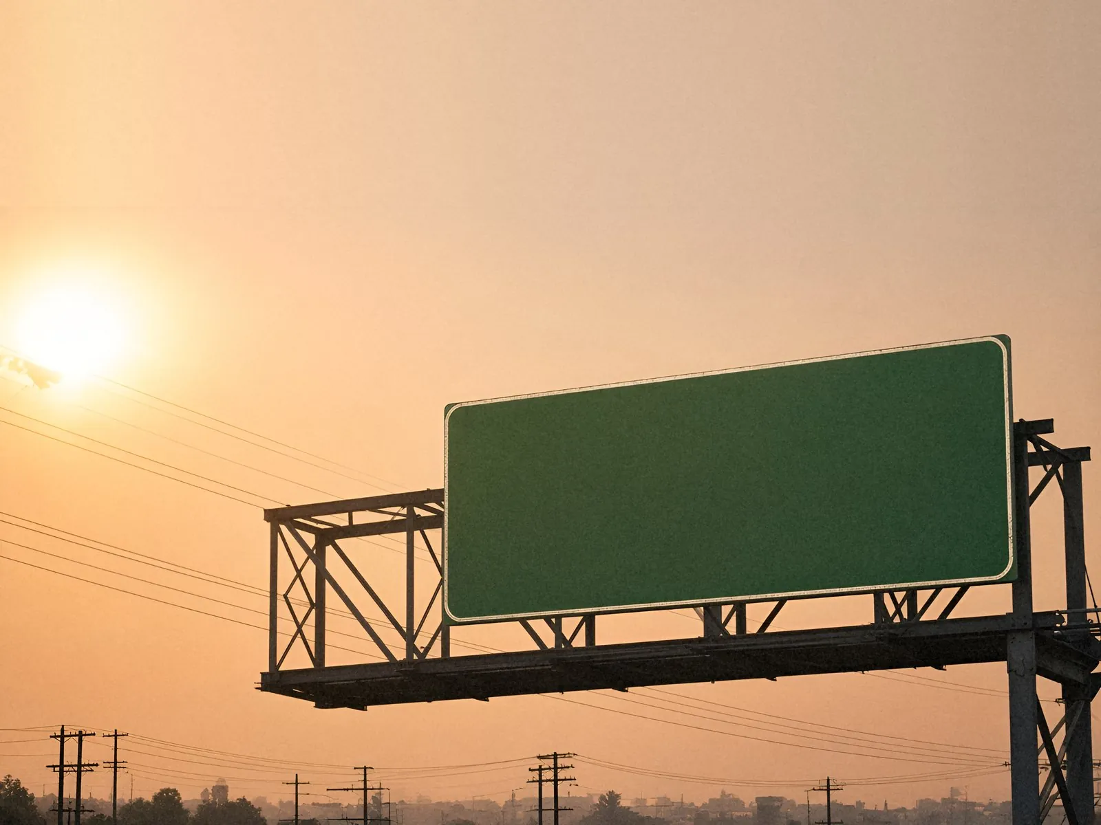 A blank green freeway sign against a purple and orange dusk sky